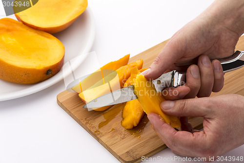 Image of Close-up Of Two Hands Peeling Juicy Mango Pieces