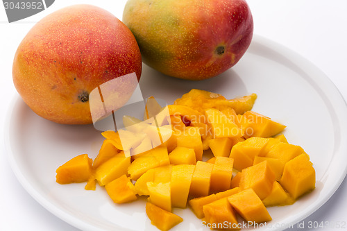 Image of Juicy Mango Dice And Two Entire Mangos On A Plate