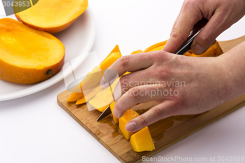 Image of Mango Wedges Being Diced On A Wooden Cutting Board