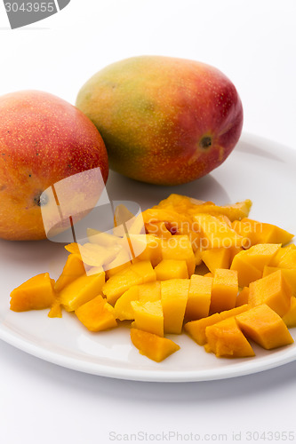 Image of Mango Cubes And Two Whole Mangos On A White Plate