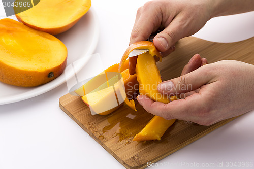 Image of Hands Separating Mango Fruit Flesh From Its Skin
