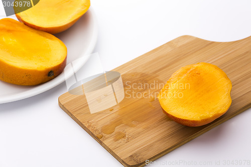 Image of Third Of A Mango And Its Juice On Wooden Board