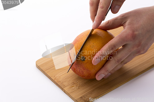 Image of Kitchen Knife Sinking Into Mango For A First Cut