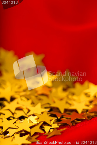 Image of Gold stars on red fabric. macro