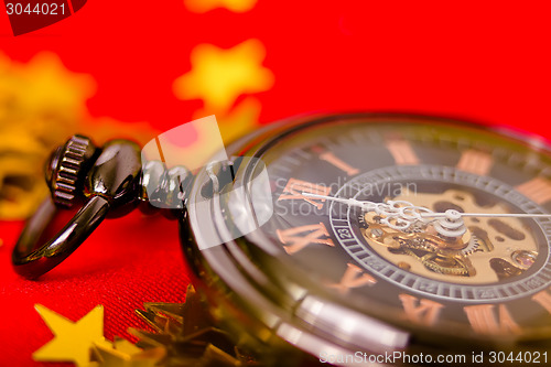 Image of Christmas card. vintage watch on a red background with golden de