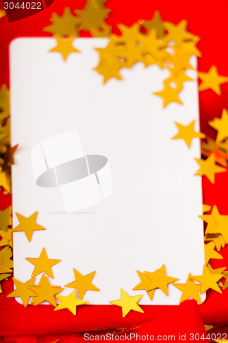 Image of Golden stars and white card on red cloth. macro