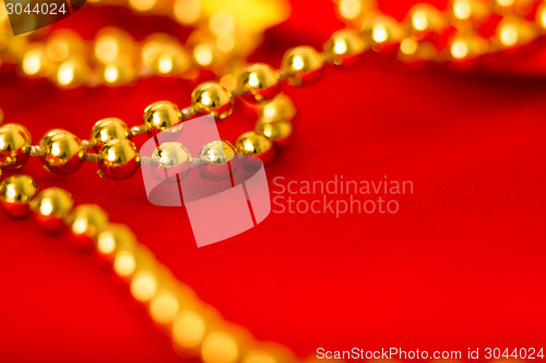 Image of Gold beads on red fabric. macro