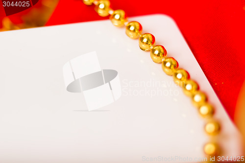Image of Gold beads and white card on red cloth. macro
