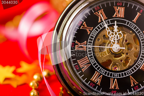 Image of Christmas card. vintage watch on a red background with golden de