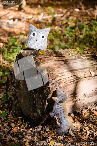 Image of Soft toy dog is chasing an owl in autumn forest