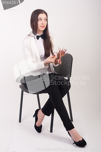 Image of Attractive businesswoman with cash sits on chair