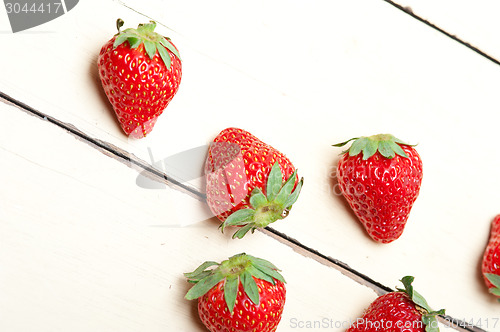 Image of fresh organic strawberry over white wood