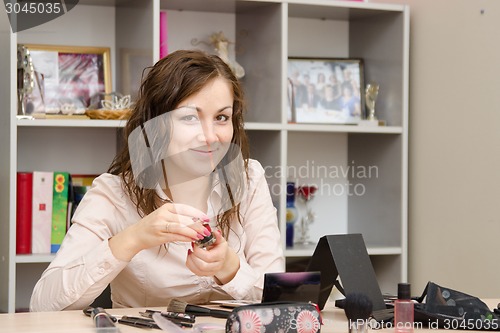 Image of Girl on office work delves into cosmetics