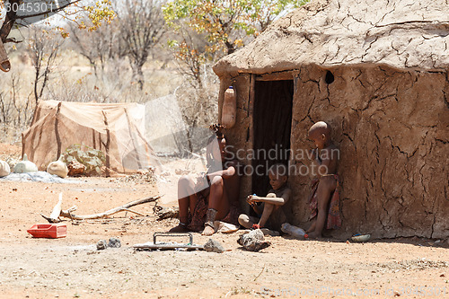 Image of Himba woman with childs on the neck in the village