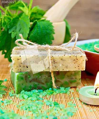 Image of Soap homemade and candle with nettles in mortar on board