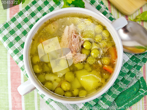 Image of Soup of green peas with meat on tablecloth