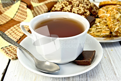Image of Tea in white cup with different cookies on light board