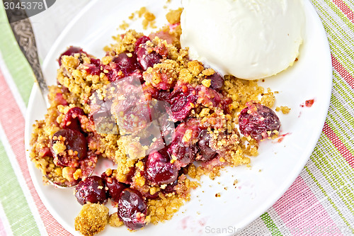 Image of Crumble cherry in plate with spoon on tablecloth