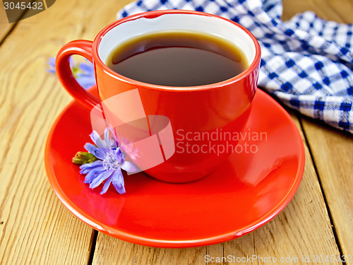 Image of Chicory drink in red cup with napkin and flower on board