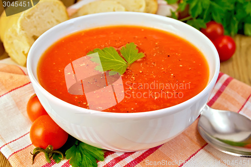 Image of Tomato soup in bowl on napkin with bread