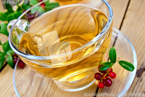 Image of Tea with lingonberry in glass cup on board