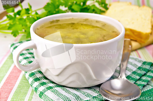 Image of Soup of green peas with bread on tablecloth
