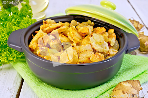 Image of Jerusalem artichokes roasted in pan with lid on light board