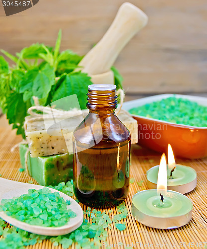 Image of Oil and candle with nettles in mortar on board