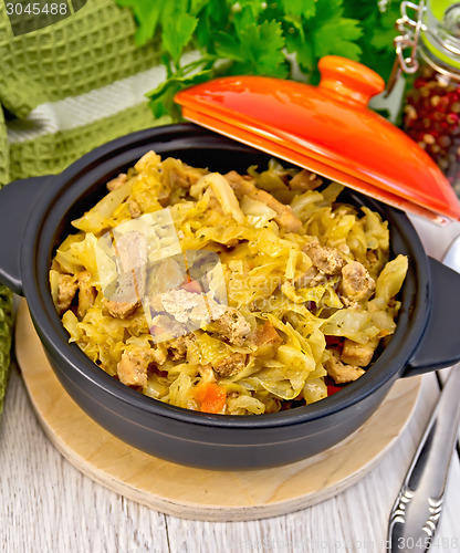 Image of Cabbage stew with meat in black pot on board