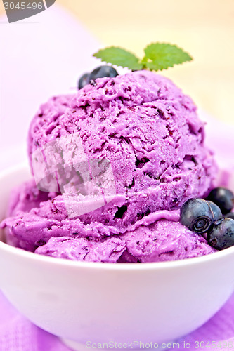 Image of Ice cream blueberry with mint in bowl on napkin