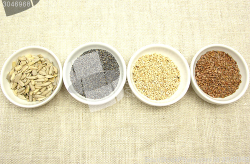 Image of Four bowl with different seeds on a beige background