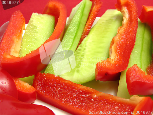 Image of Slitted red pepper and cucumber on a white plate and placemat