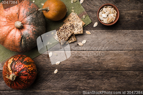 Image of Rustic pumpkins with seeds and cookies on wooden table