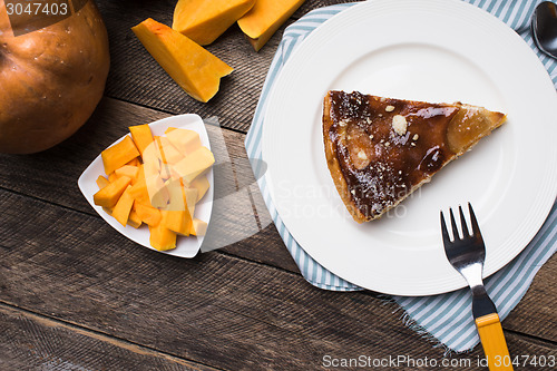 Image of pie on plate and pieces of pumpkin in Rustic style