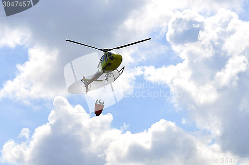 Image of The small yellow helicopter in the sky.