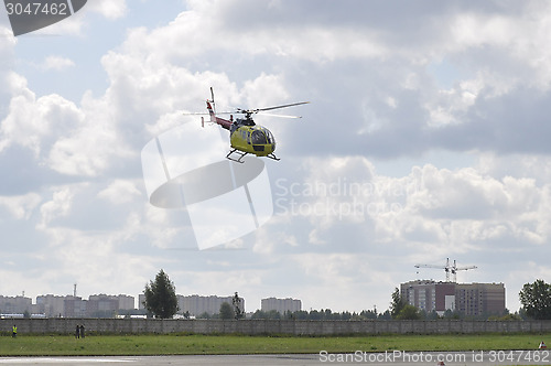 Image of The small yellow helicopter in the sky.