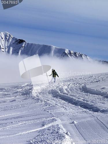 Image of Snowboarder downhill on off-piste slope in sunny day