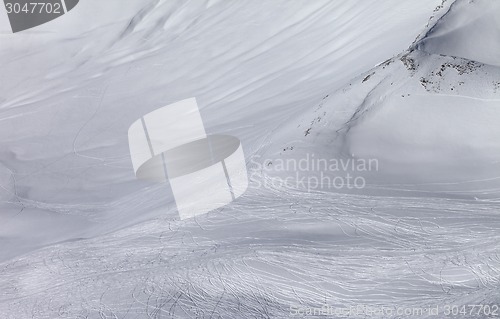 Image of Off-piste slope with traces of skis and snowboards in sun day