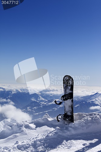 Image of Snowboard in snow on off-piste slope at sun day