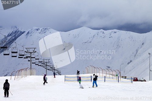 Image of Ski slope with skiers and snowboarders in evening