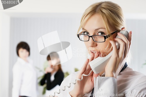 Image of Attractive woman calls by wire phone in office