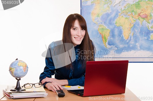 Image of Young girl working on a laptop in the office of travel agency