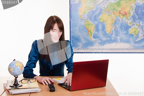 Image of employee of a travel agency is working on laptop