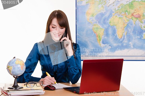 Image of Travel agent writes in a notebook on the phone