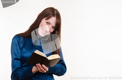 Image of Business woman writing in a notebook on the phone