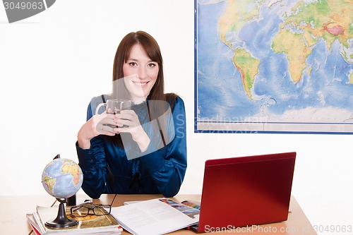 Image of The manager of travel agency is drinking tea in workplace