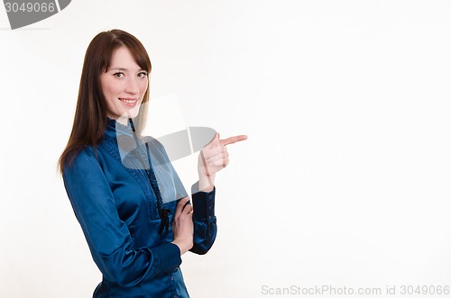 Image of Young girl in a blue blouse pointing at empty space on left