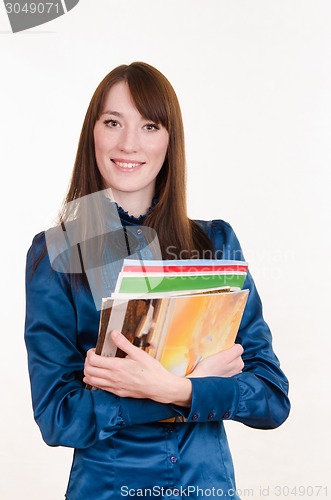 Image of Young girl standing with a stack of magazines