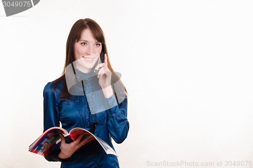 Image of Young girl with a magazine in his hand talking on phone