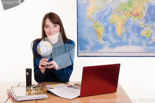 Image of Cartographer sitting at the table with a globe in his hands